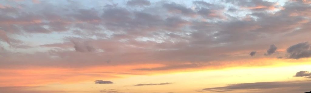 Sunset sky with orange, gray and pink thin clouds