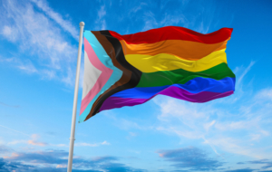 Progress LGBTQ rainbow flag waving in the wind at cloudy sky. Freedom and love concept. Pride month. activism, community and freedom Concept. Copy space. 3d illustration.